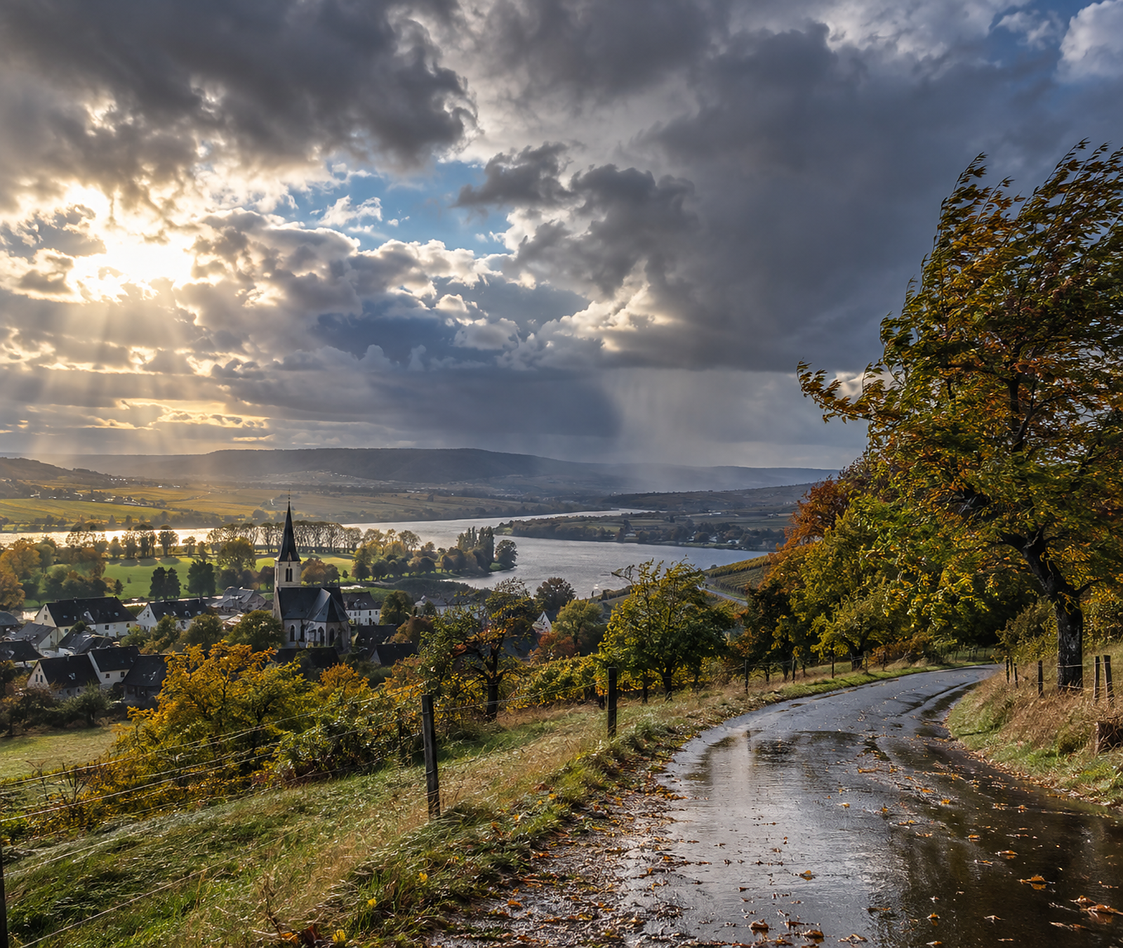 Herbstliche deutsche Landschaft mit nasser Strasse, kräftigen Wolken und sonnigen Auflockerungen