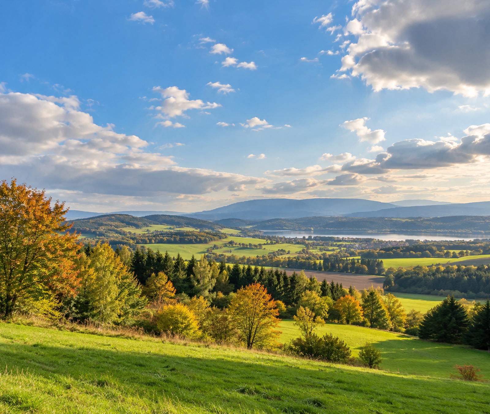 Herbstliches deutsches Hügelland mit Wiesen, Wäldern und freundlichem Himmel