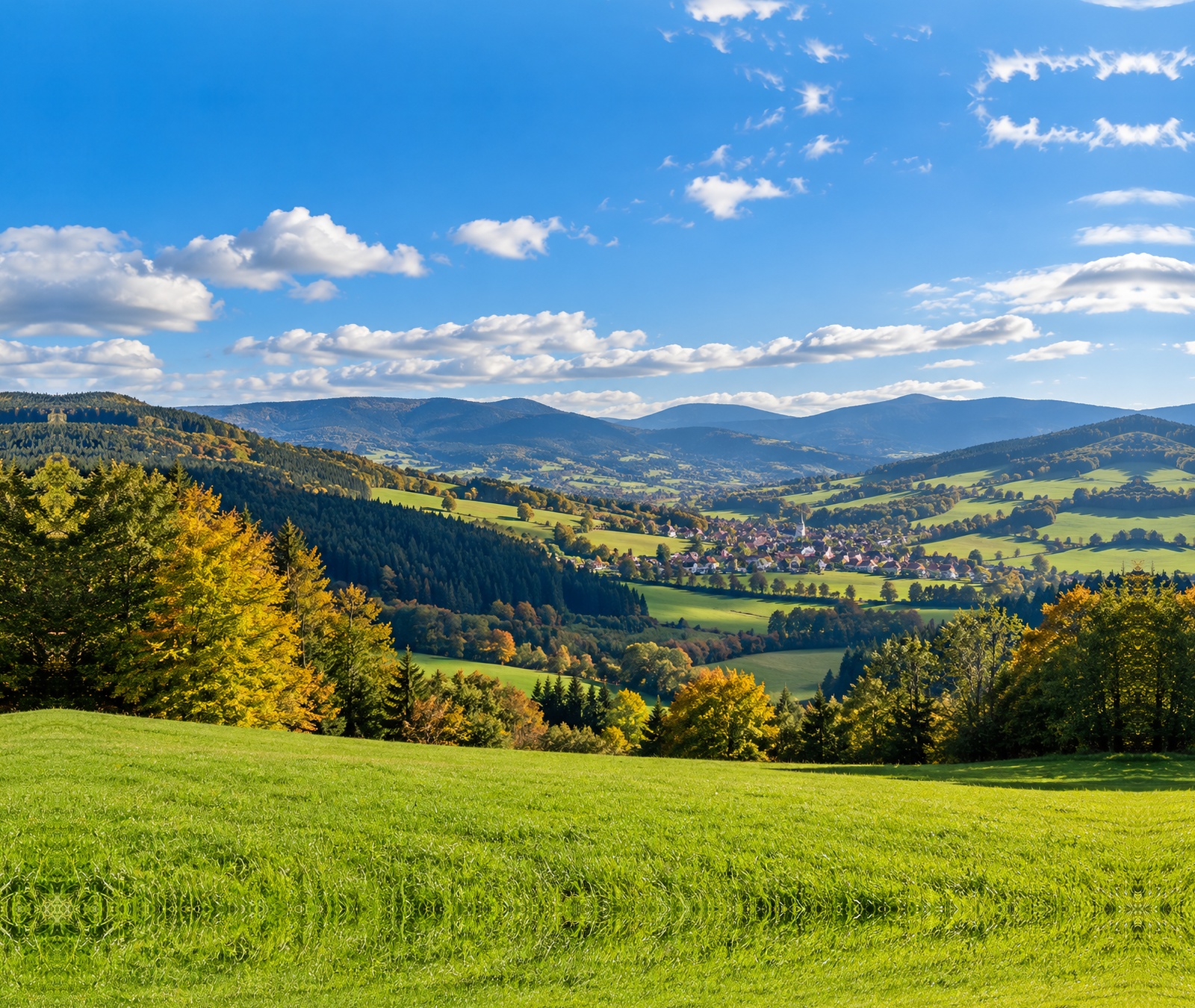 Symbolbild einer spätsommerlich-milden deutschen Hügellandschaft mit Sonne und lockeren Wolken