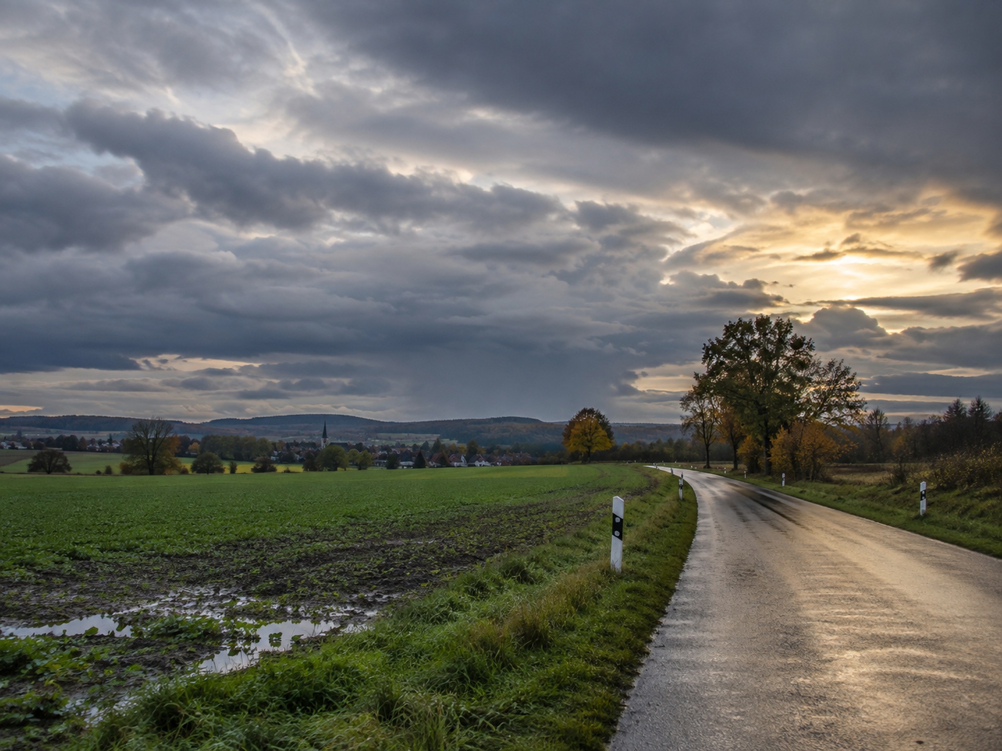 Ländliche deutsche Strasse nach Regen unter dichtem Wolkenhimmel