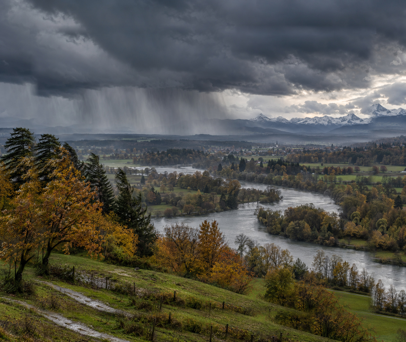 Herbstliches deutsches Flusstal unter dunklen Regenwolken als Symbolbild für die heranziehende Kaltfront.